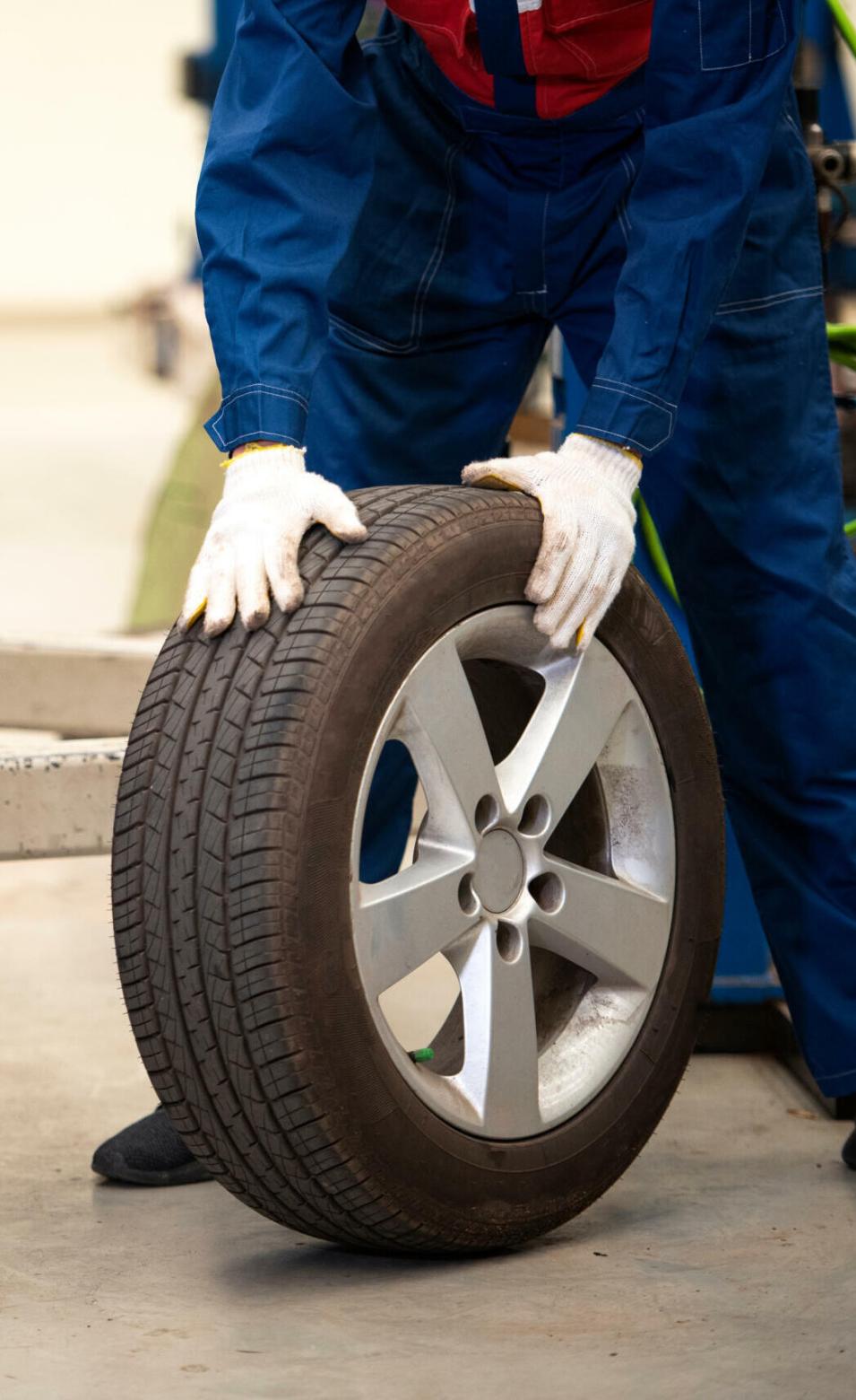 Mechanic holds tires at the garage. Changing tires in a car service center in Asia